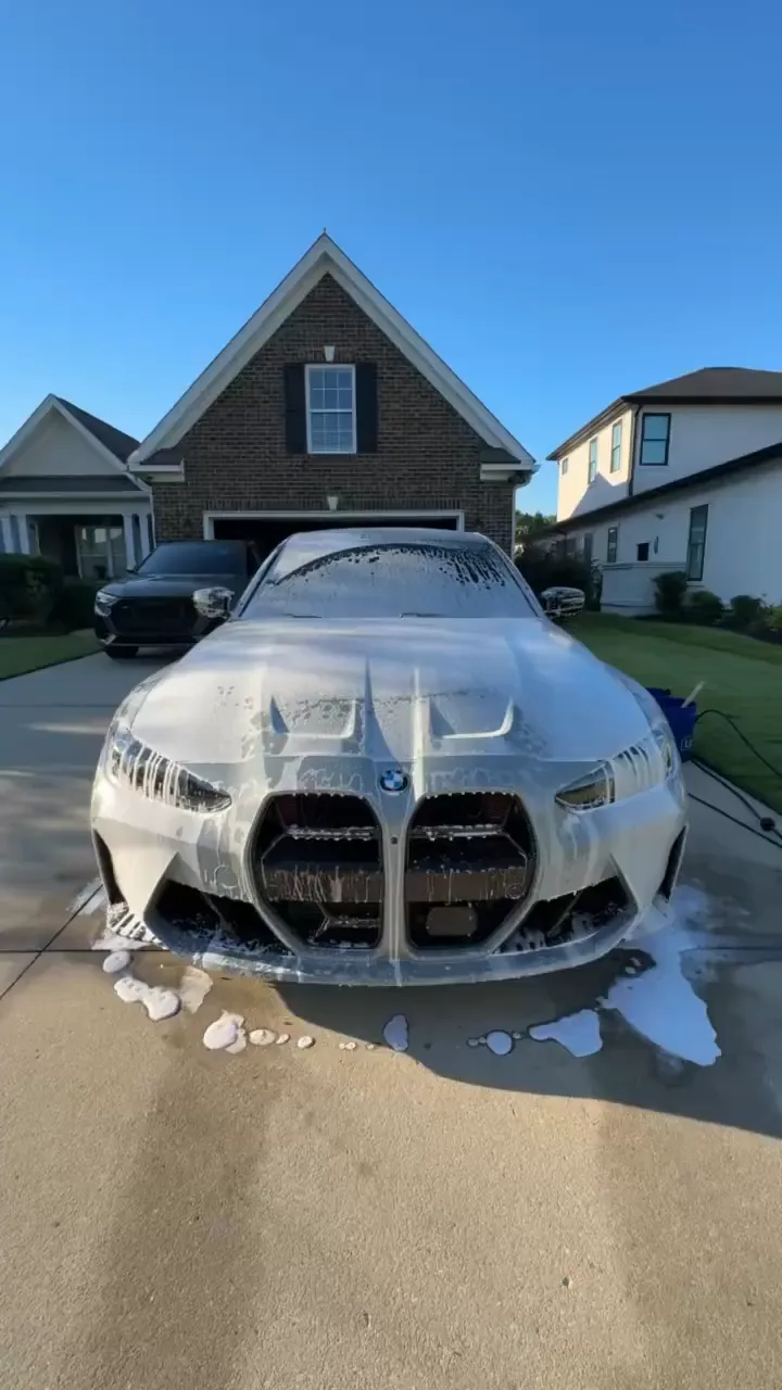 BMW M3 covered in snow foam in a driveway