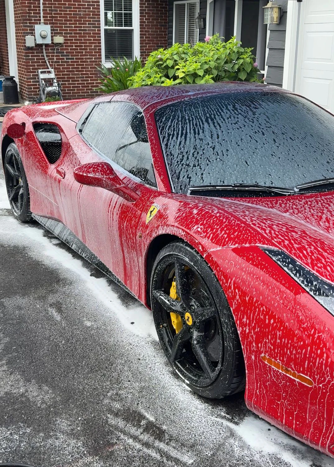 Red Ferrari covered in snow foam during an exterior wash