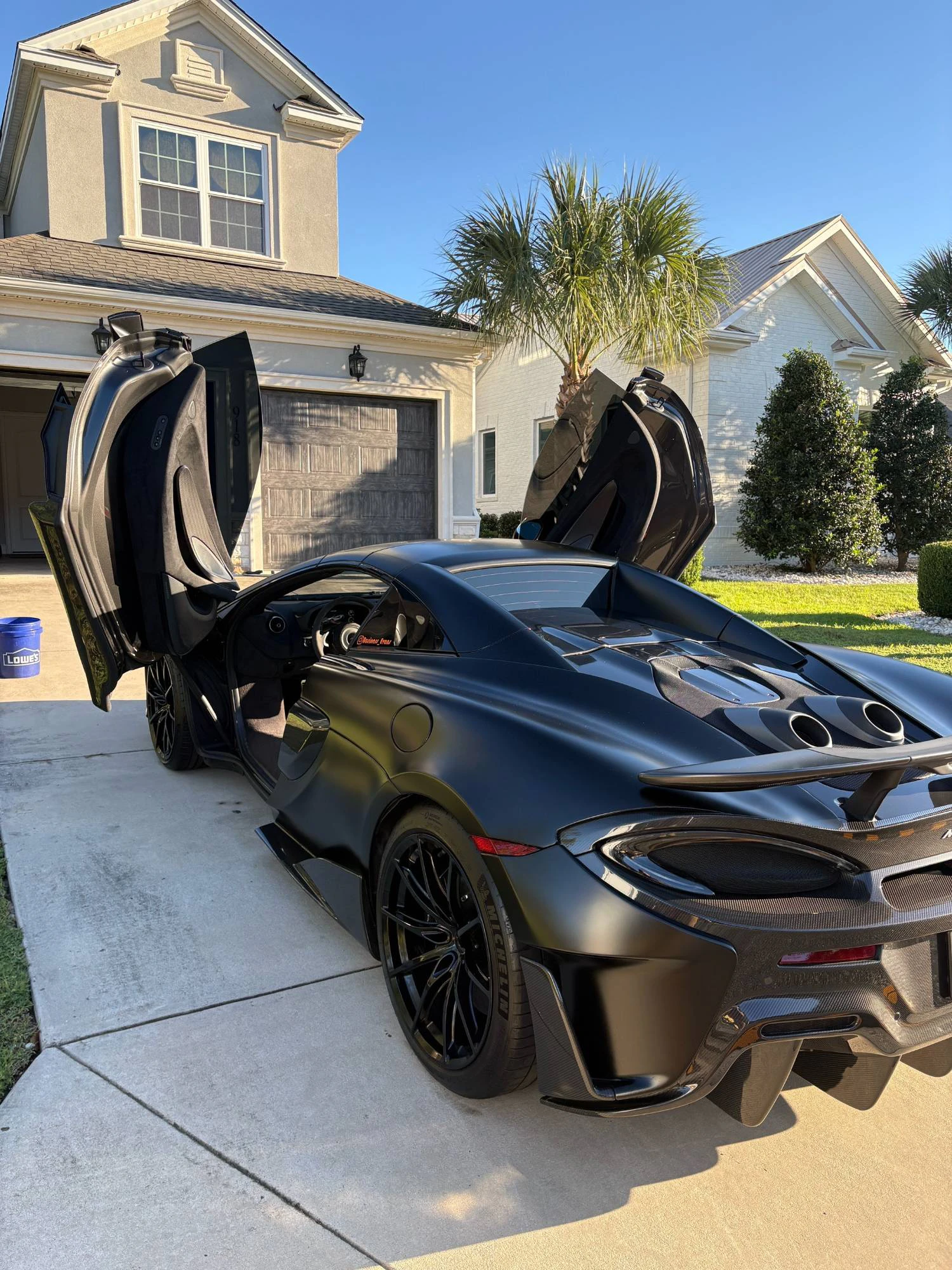 Matte black McLaren 600LT with its doors up after a full detail